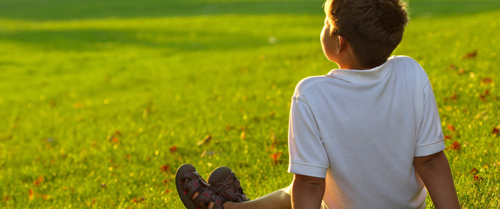 little boy sitting on grass