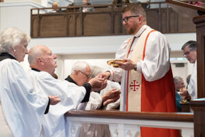 Stoda receives Communion from Bishop Edgar